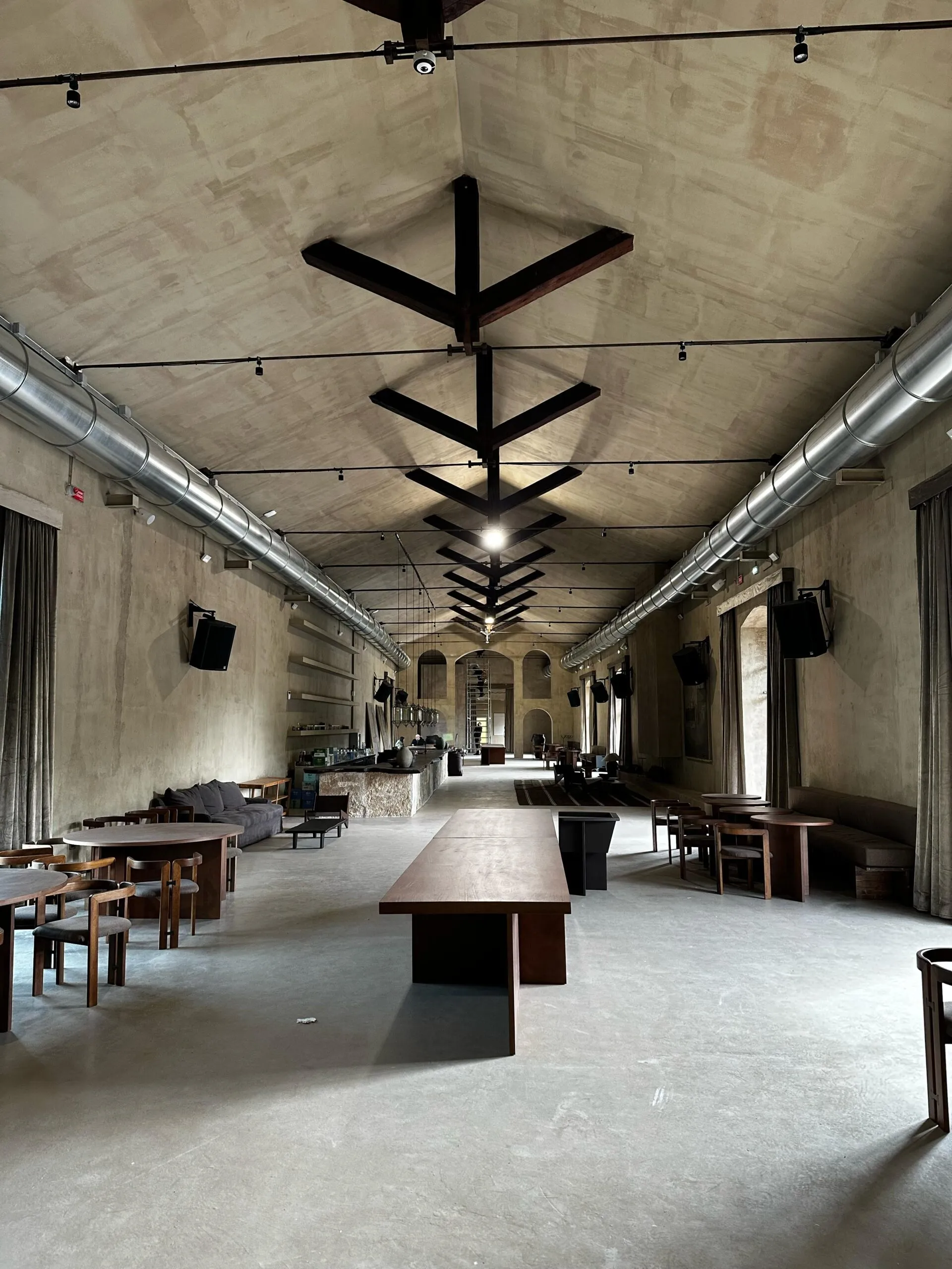 Sala interna del locale con arredi in legno, pareti in cemento e impianti a vista