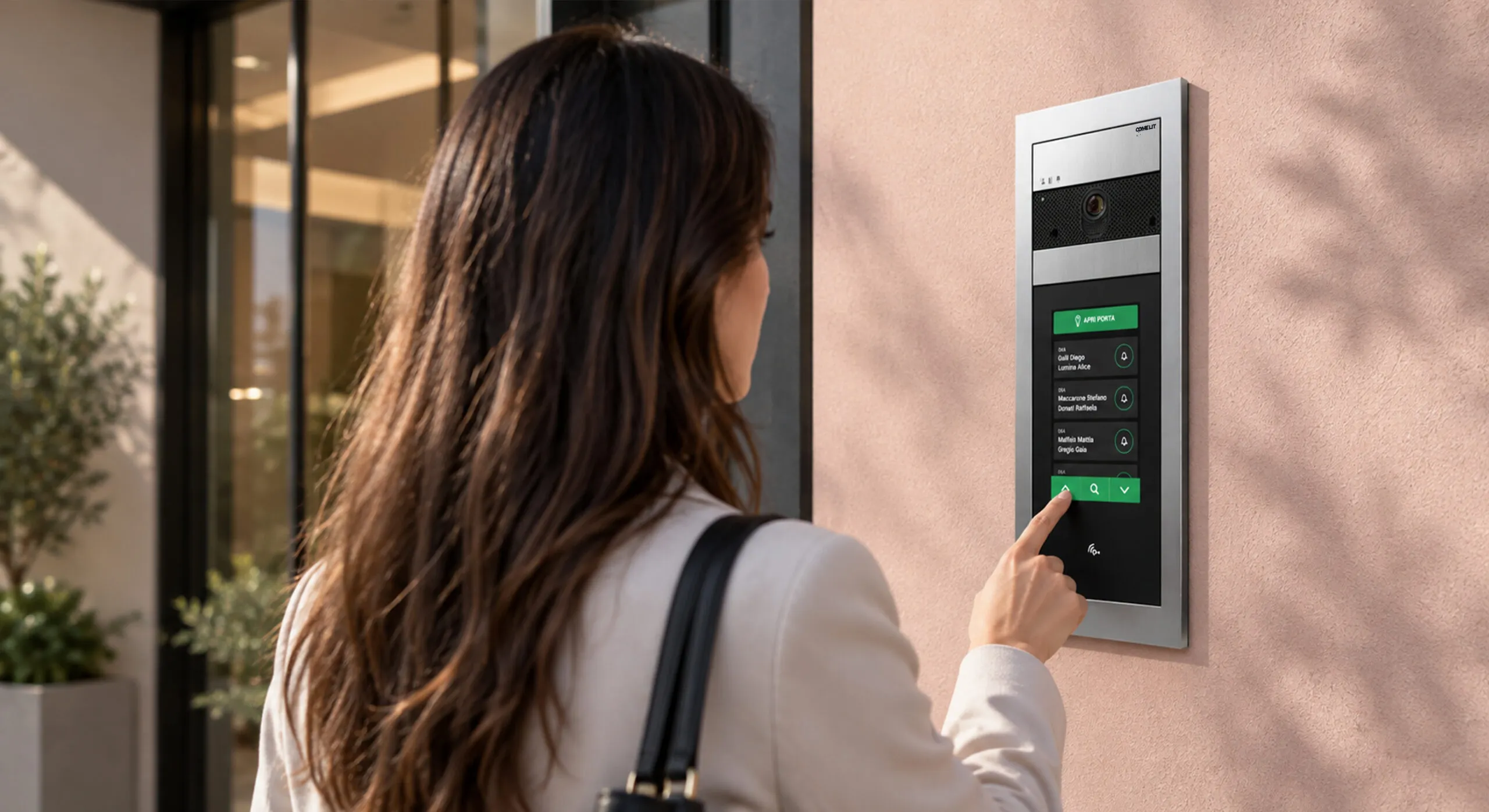 Donna utilizza un videocitofono IP Comelit con touchscreen per aprire la porta