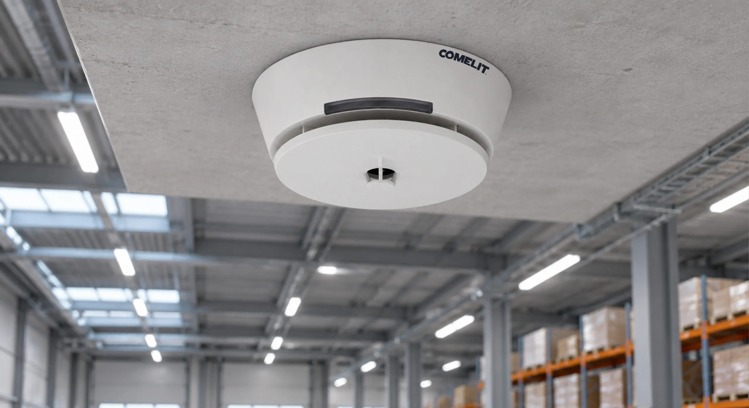 Rivelatore ottico di fumo Comelit installato a soffitto in un edificio commerciale