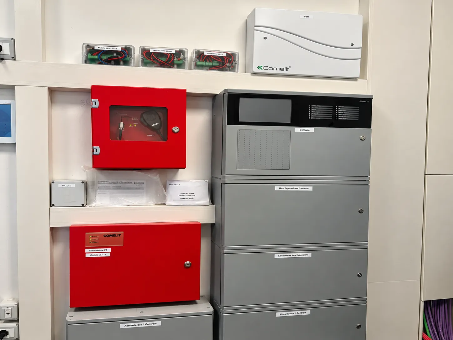 Centrale di rivelazione incendi Comelit con box di espansione, alimentatori, base microfonica EVAC e modulo GSM nel locale tecnico